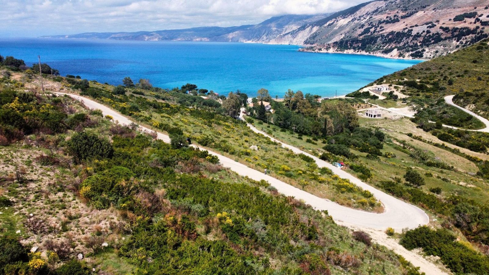 Hillside plots above Myrtos bay in Kefalonia with a winding road