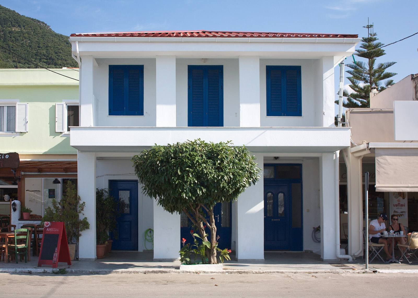 A white two-storey house with blue shutters in Sami, Kefalonia
